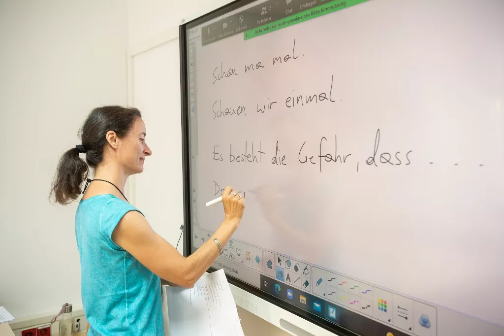 Eine Mitarbeiterin der Deutschkurse erklärt die Fachbegriffe an einer Tafel