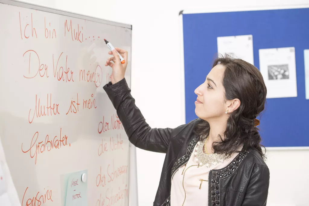 Eine Mitarbeiterin vin Deutsch in Graz die etwas auf die Tafel schreibt