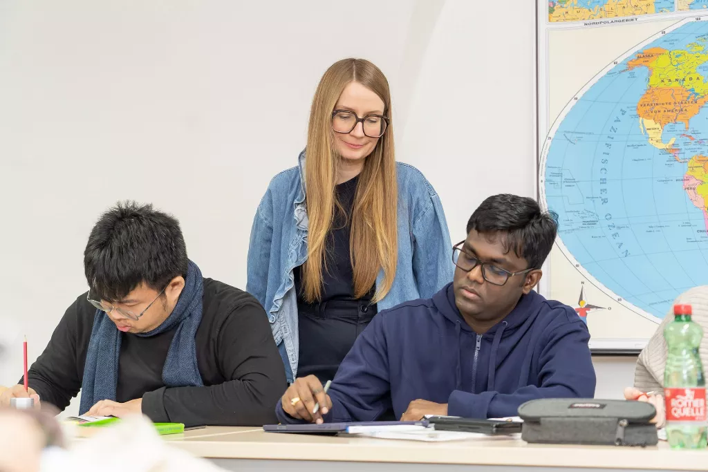 Eine Mitarbeiterin unterstützt in einem Deutschkurs die Teilnehmer