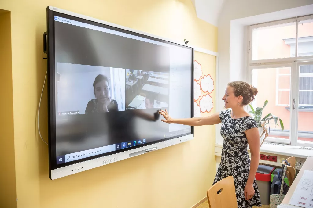 Eine Frau zeigt auf einen Fernsehbildschirm