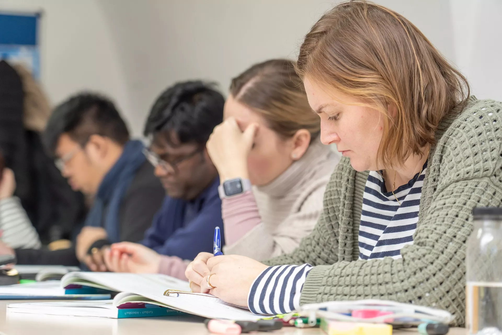 Konversationskurs Deutsch: Eine Gruppe von Teilnehmern schreiben etwas auf