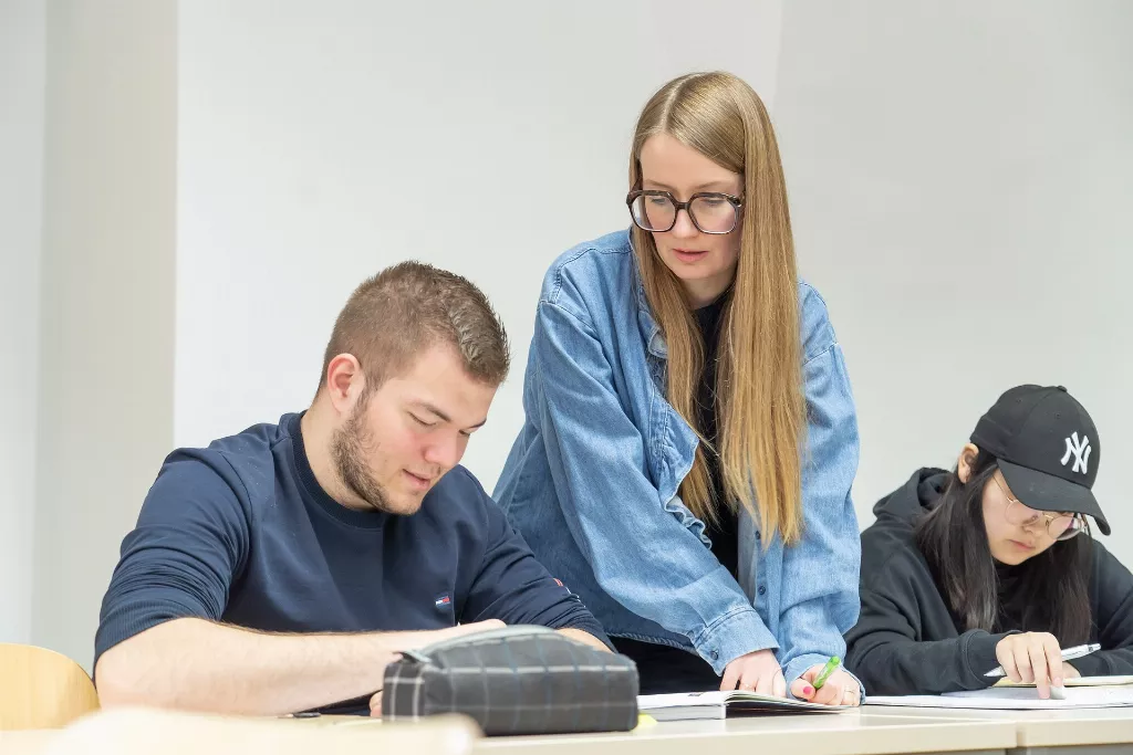 Sprachkurs Deutsch bei Graz: Mitarbeiterin schaut bei Teilnehmer wie es bei der Modellprüfung geht