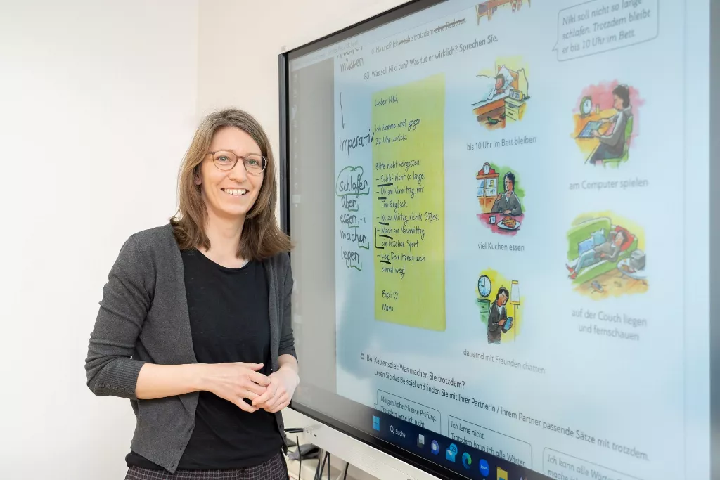 Eine Deutsch in Graz Mitarbeiterin die eine Präsentation auf dem Bildschirm haltet