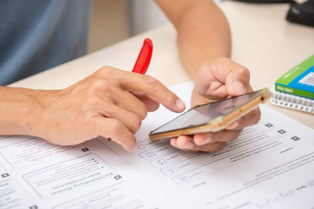 Eine Person, die an einem Schreibtisch sitzt und ein Mobiltelefon benutzt