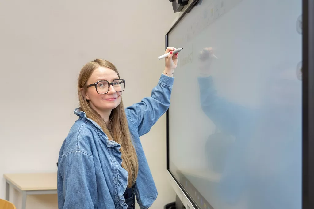 Eine Frau mit Brille schreibt auf einer weißen Tafel