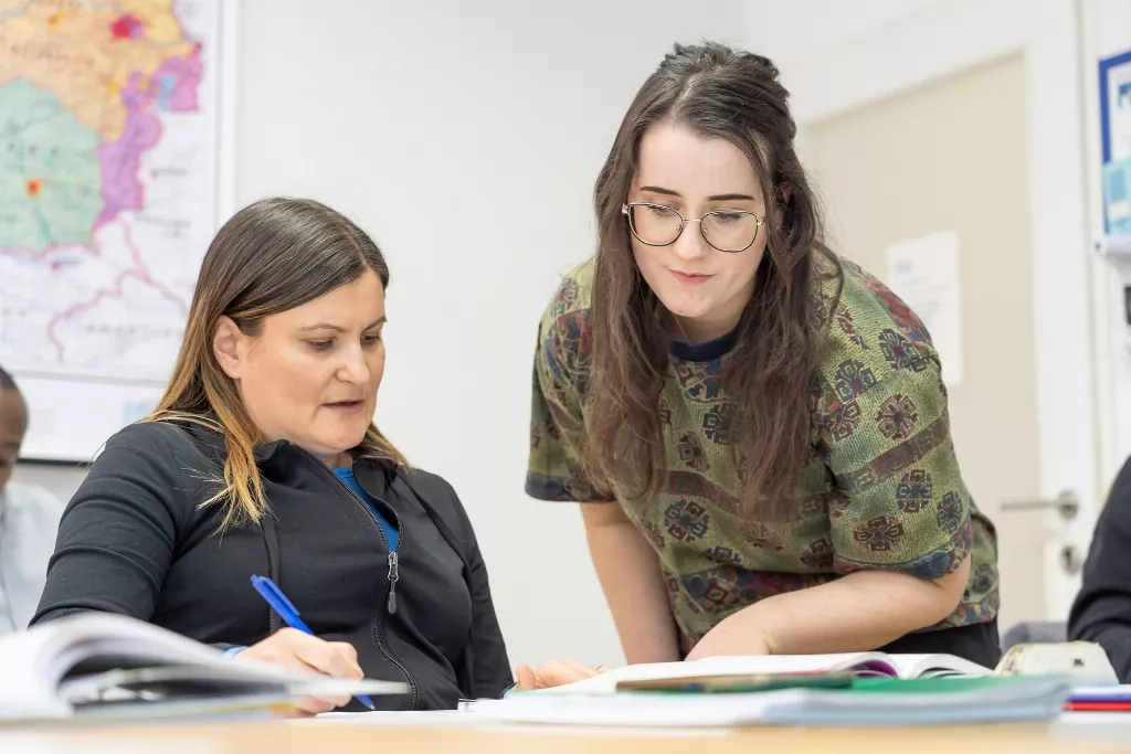 Sprachkurs Deutsch: Die Mitarbeiterin unterstützt die Teilnehmerin bei der Ausarbeitung Ihrer Aufgaben