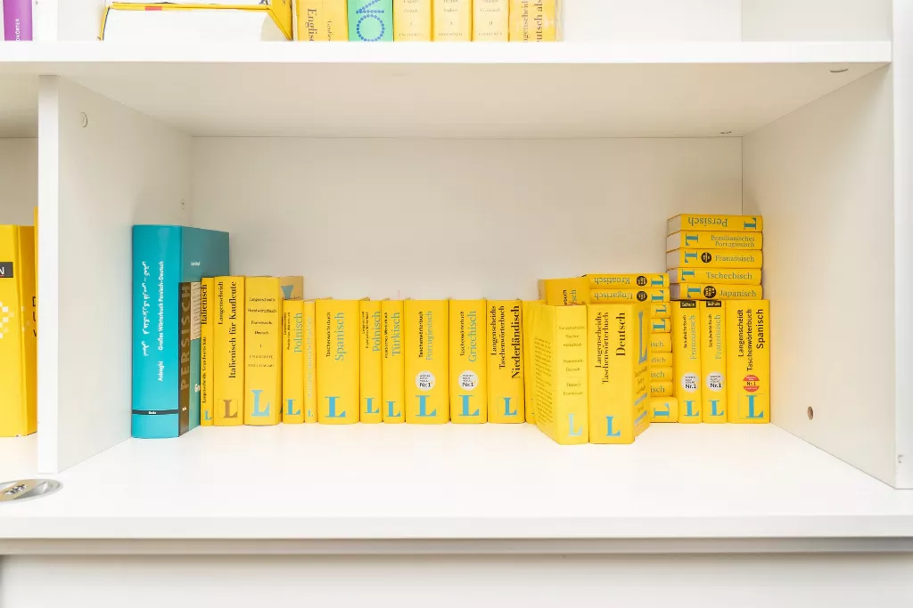 Eine Reihe gelber Bücher auf einem weißen Regal