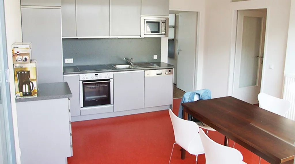 Eine Küche mit Tisch und Stühlen und einer Mikrowelle